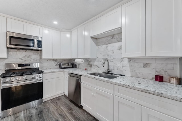 kitchen featuring decorative backsplash, dark hardwood / wood-style flooring, stainless steel appliances, sink, and white cabinets