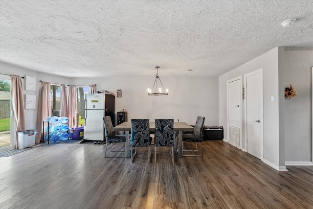 dining space with dark hardwood / wood-style flooring, a textured ceiling, and a notable chandelier