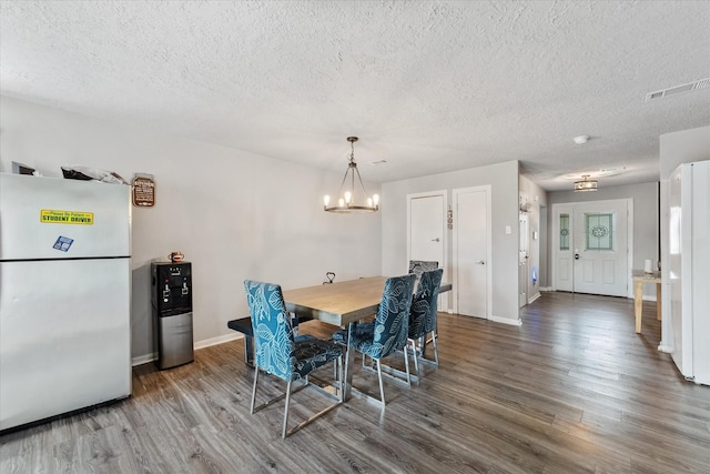 dining space with a notable chandelier, a textured ceiling, and hardwood / wood-style flooring