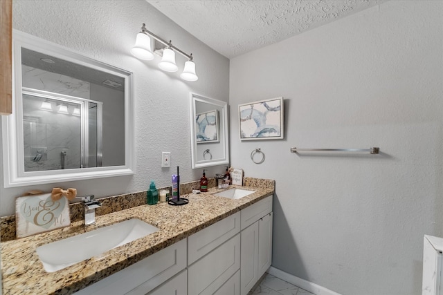 bathroom with vanity, a shower with shower door, and a textured ceiling