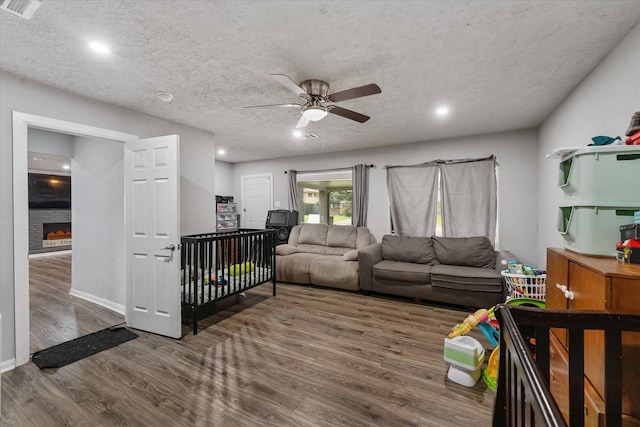 living room with ceiling fan, dark hardwood / wood-style flooring, and a textured ceiling