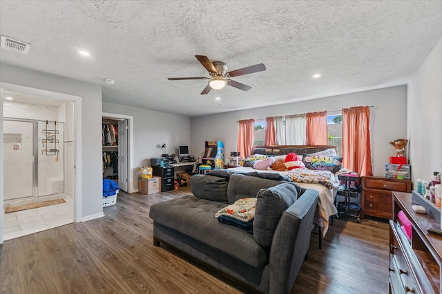 bedroom featuring hardwood / wood-style floors, a walk in closet, ceiling fan, a textured ceiling, and a closet