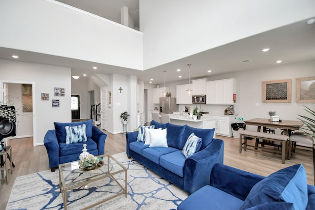 living room featuring a towering ceiling and light wood-type flooring