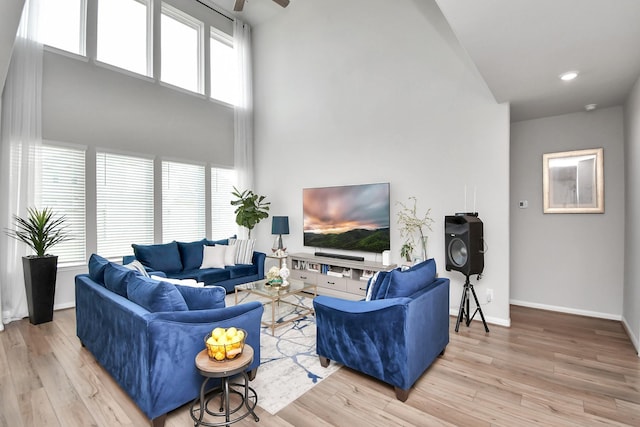 living room with a towering ceiling and light hardwood / wood-style flooring