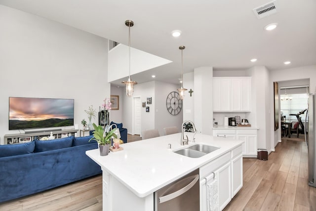 kitchen with appliances with stainless steel finishes, light wood-type flooring, a kitchen island with sink, sink, and hanging light fixtures