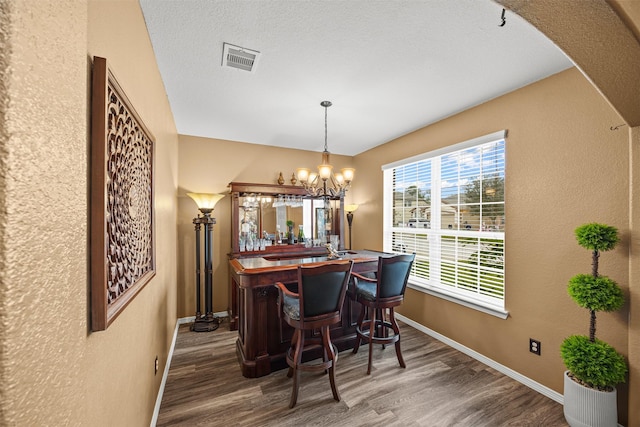 bar featuring pendant lighting, hardwood / wood-style floors, a chandelier, and a textured ceiling