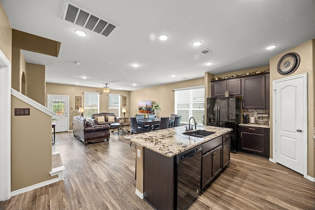 kitchen with black appliances, plenty of natural light, a center island with sink, and dark brown cabinetry