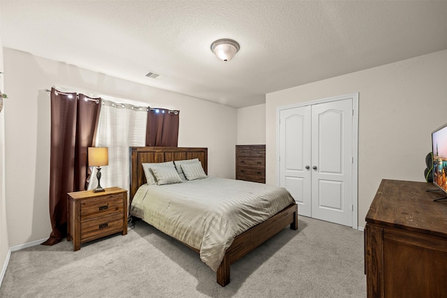 carpeted bedroom with a textured ceiling and a closet