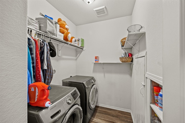 clothes washing area featuring a textured ceiling, separate washer and dryer, and dark wood-type flooring