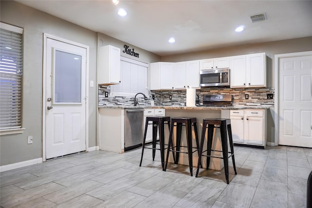 kitchen featuring white cabinets, a kitchen breakfast bar, and stainless steel appliances