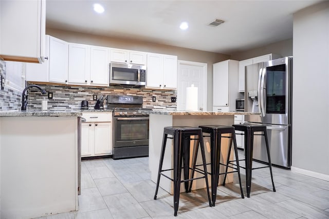 kitchen featuring white cabinets, a kitchen breakfast bar, and appliances with stainless steel finishes