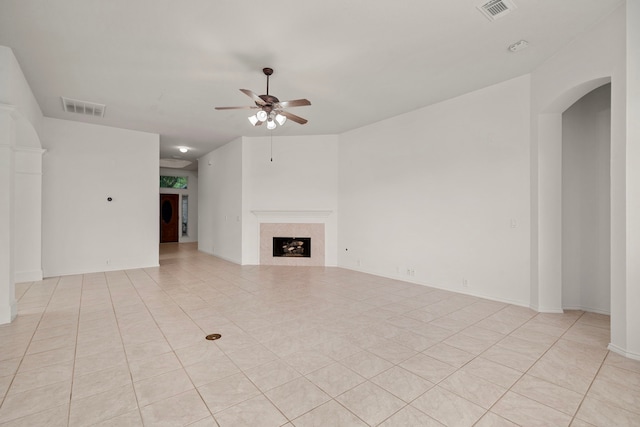 unfurnished living room featuring ceiling fan, light tile patterned floors, and a tiled fireplace