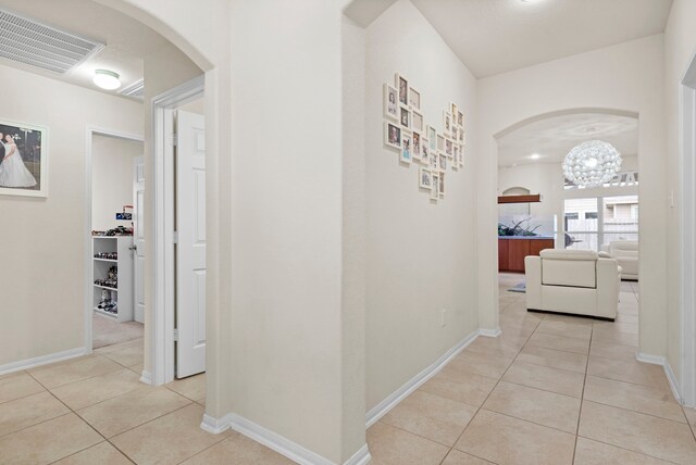 hall with an inviting chandelier and light tile patterned floors