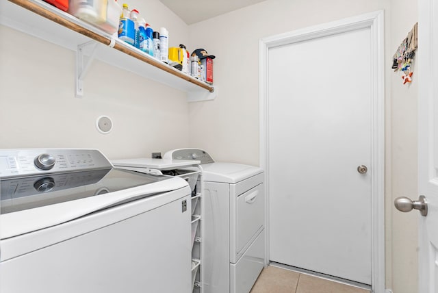 clothes washing area featuring washing machine and clothes dryer and light tile patterned floors