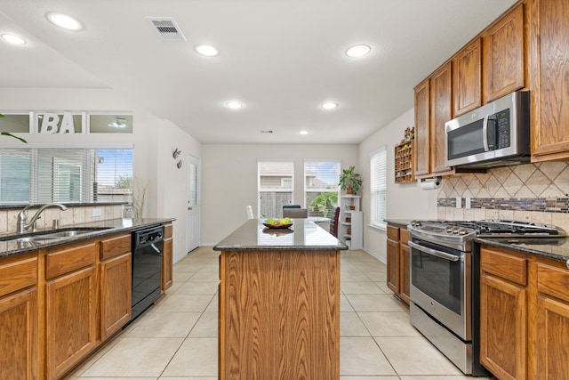 kitchen featuring stainless steel appliances, a center island, light tile patterned flooring, dark stone countertops, and backsplash