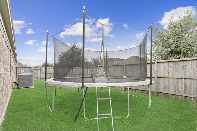 view of yard with central air condition unit and a trampoline