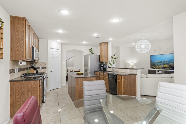 kitchen featuring appliances with stainless steel finishes, kitchen peninsula, light tile patterned floors, sink, and backsplash