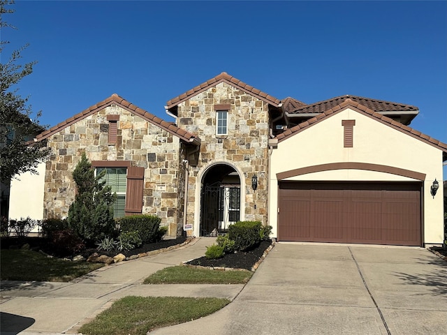 view of front of house featuring an attached garage, driveway, stone siding, a tiled roof, and stucco siding