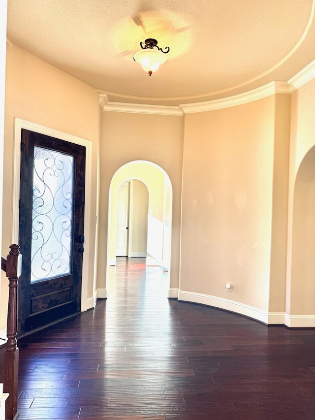 entrance foyer featuring a textured ceiling, dark hardwood / wood-style floors, and ornamental molding