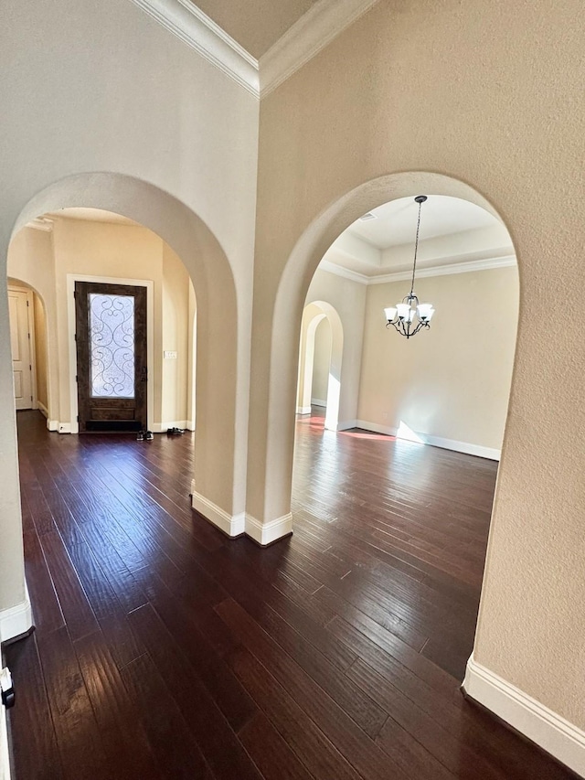 interior space with dark wood-type flooring, a chandelier, and ornamental molding