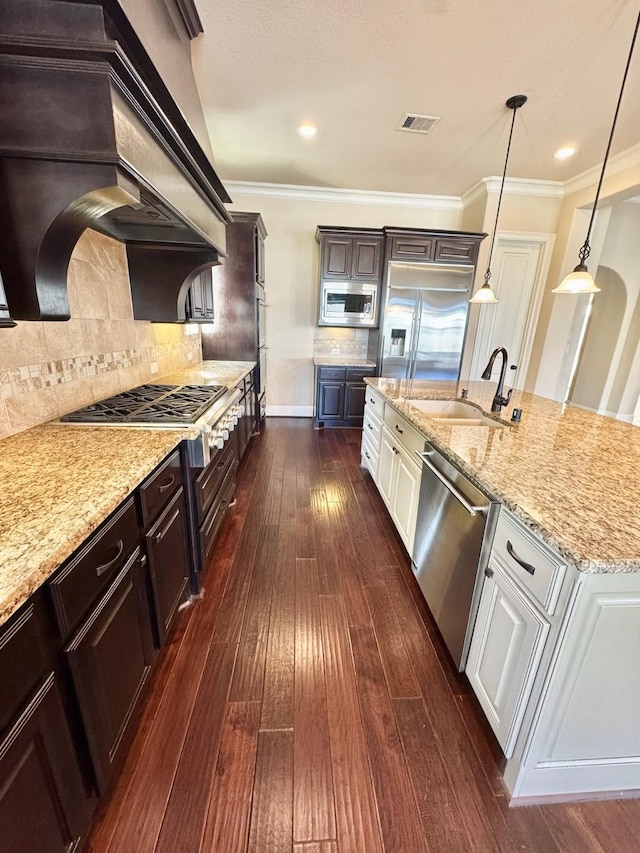 kitchen featuring sink, pendant lighting, built in appliances, dark hardwood / wood-style floors, and white cabinetry