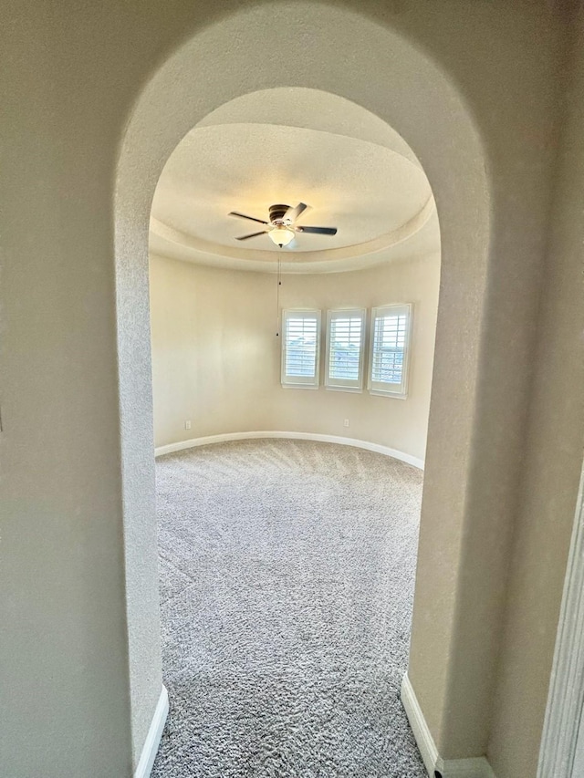 spare room featuring carpet, a tray ceiling, and ceiling fan