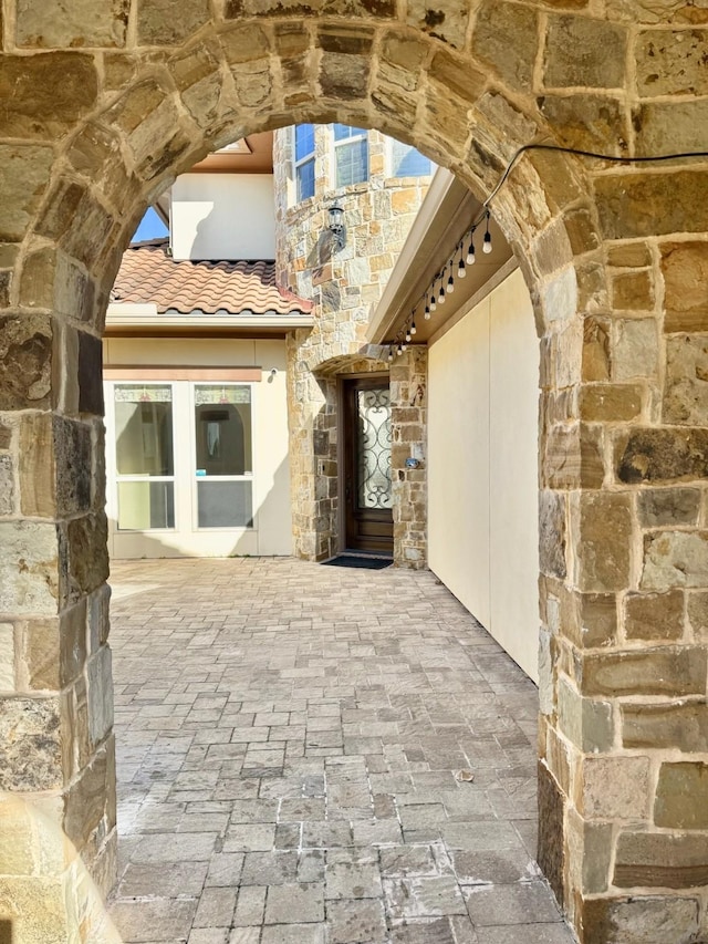 view of exterior entry with stone siding and a tile roof