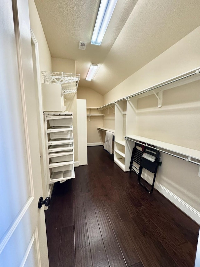 spacious closet featuring dark hardwood / wood-style flooring and lofted ceiling