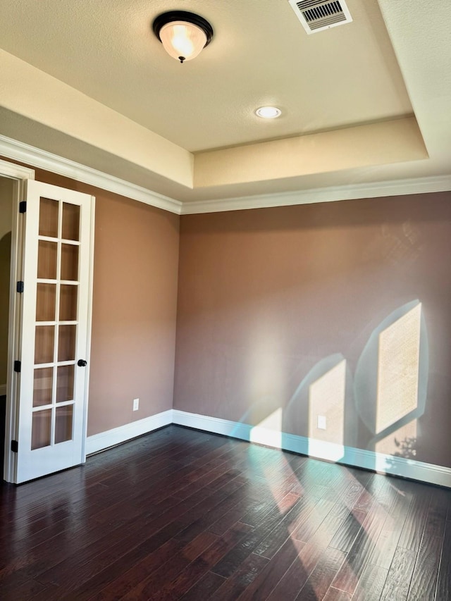 spare room featuring a raised ceiling, crown molding, dark hardwood / wood-style flooring, and french doors