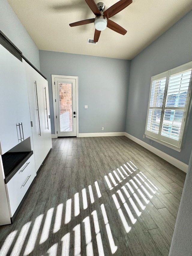 unfurnished living room with a wealth of natural light, dark hardwood / wood-style flooring, and ceiling fan