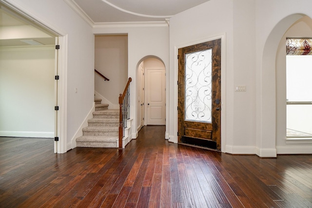 entrance foyer featuring arched walkways, dark wood-style flooring, baseboards, ornamental molding, and stairway