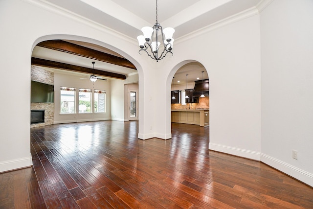 unfurnished living room featuring dark wood-type flooring, a stone fireplace, baseboards, and ceiling fan with notable chandelier