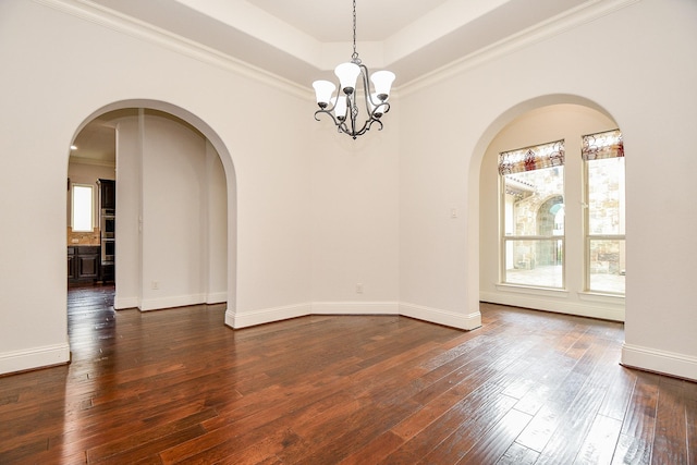 empty room with arched walkways, baseboards, dark wood-style floors, a tray ceiling, and an inviting chandelier