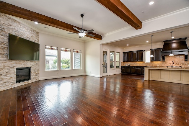 unfurnished living room with a stone fireplace, dark wood-style flooring, and beam ceiling