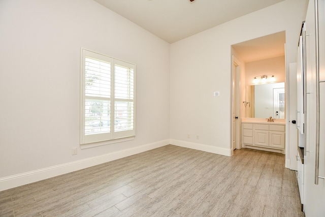 unfurnished bedroom featuring light wood-type flooring, baseboards, and a sink