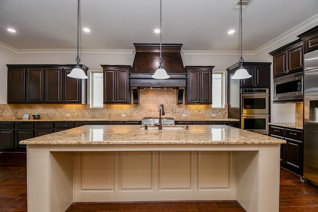 kitchen featuring dark brown cabinets, appliances with stainless steel finishes, an island with sink, and a sink