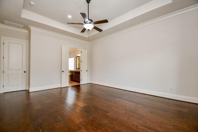 unfurnished bedroom featuring visible vents, baseboards, a raised ceiling, ensuite bath, and dark wood-type flooring