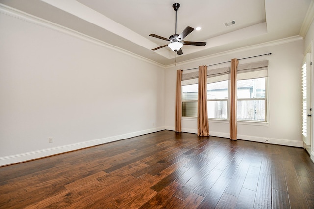 unfurnished room featuring dark wood-type flooring, visible vents, baseboards, a tray ceiling, and crown molding