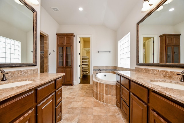 bathroom featuring a garden tub, a spacious closet, a sink, and visible vents