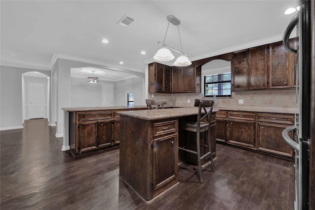 kitchen with dark brown cabinetry, a center island, dark hardwood / wood-style flooring, stainless steel fridge, and decorative light fixtures