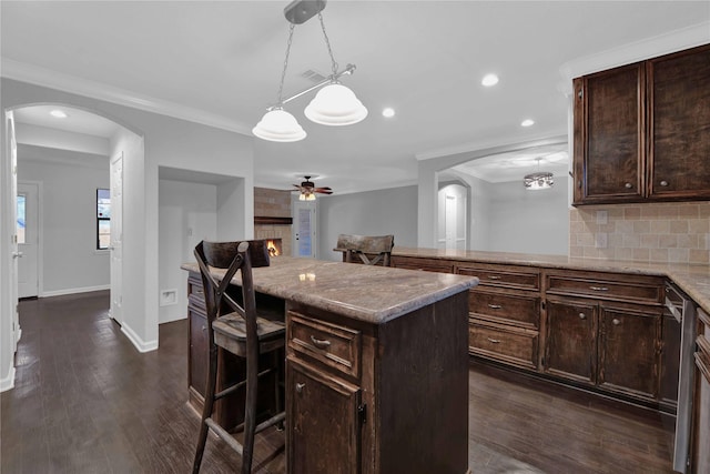 kitchen featuring tasteful backsplash, dark brown cabinets, dark hardwood / wood-style floors, a kitchen island, and a breakfast bar area