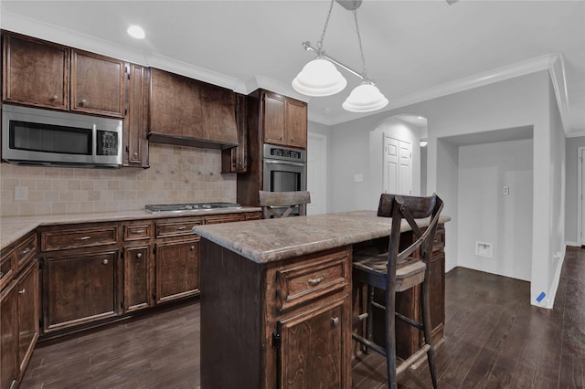 kitchen with decorative light fixtures, a kitchen island, dark hardwood / wood-style flooring, dark brown cabinetry, and stainless steel appliances