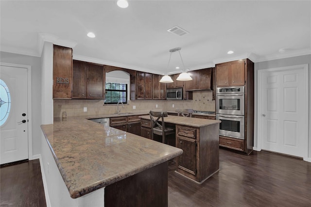 kitchen with dark brown cabinetry, a center island, dark hardwood / wood-style flooring, pendant lighting, and appliances with stainless steel finishes