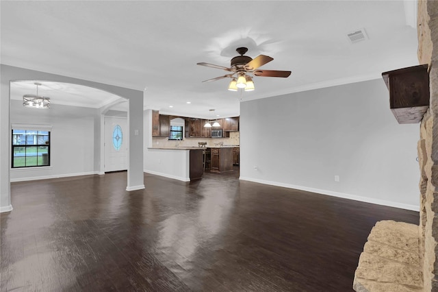 unfurnished living room with ceiling fan with notable chandelier, dark hardwood / wood-style flooring, and ornamental molding