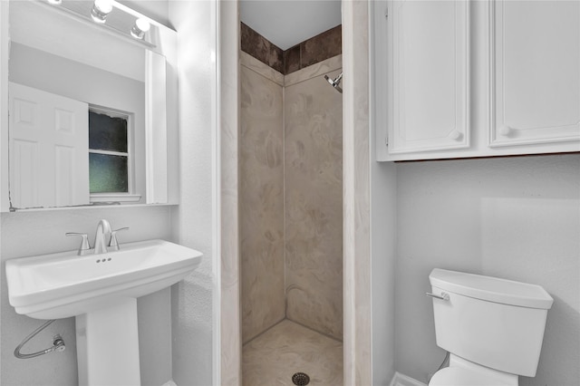 bathroom with tiled shower, toilet, and sink