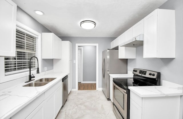 kitchen featuring sink, light stone counters, white cabinets, exhaust hood, and appliances with stainless steel finishes