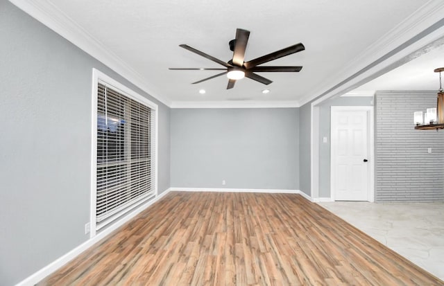 empty room with crown molding, ceiling fan with notable chandelier, wood-type flooring, and brick wall