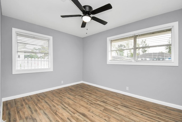 empty room with wood-type flooring, ceiling fan, and a healthy amount of sunlight