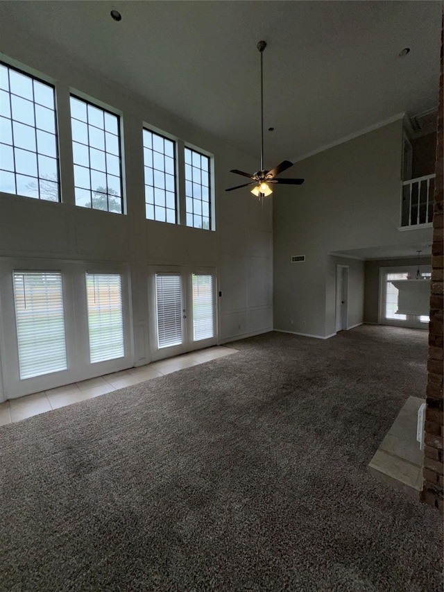 unfurnished living room featuring ceiling fan, crown molding, a towering ceiling, and carpet floors