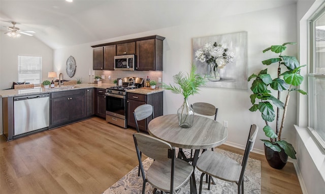 kitchen with sink, vaulted ceiling, ceiling fan, light wood-type flooring, and appliances with stainless steel finishes